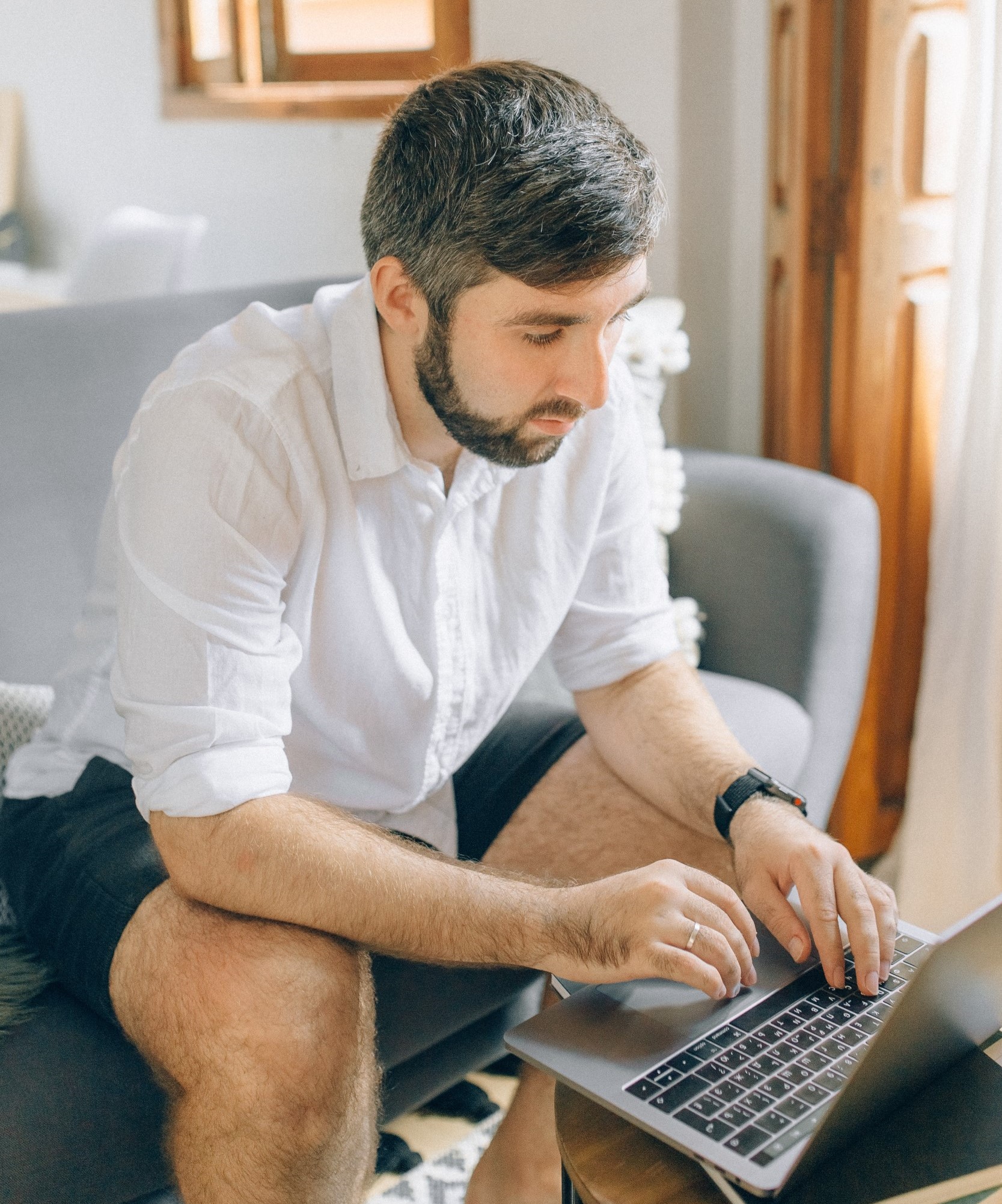 A man, who enjoys flexible working, works on the sofa with a laptop at home. 