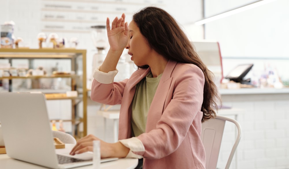 a women at work sneezes in the office into her arm