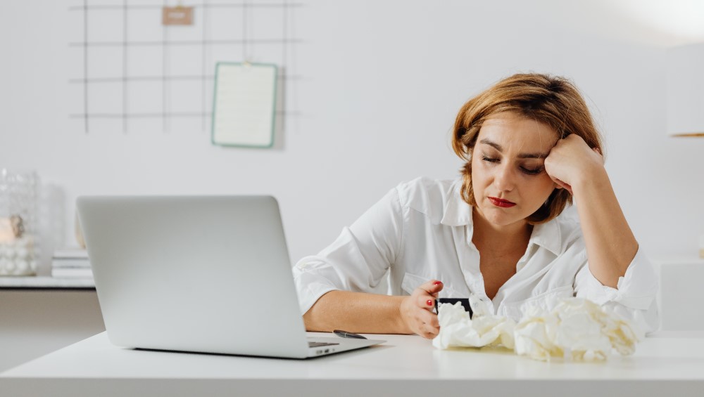 a women sits in the office on her laptop sick with tissues
