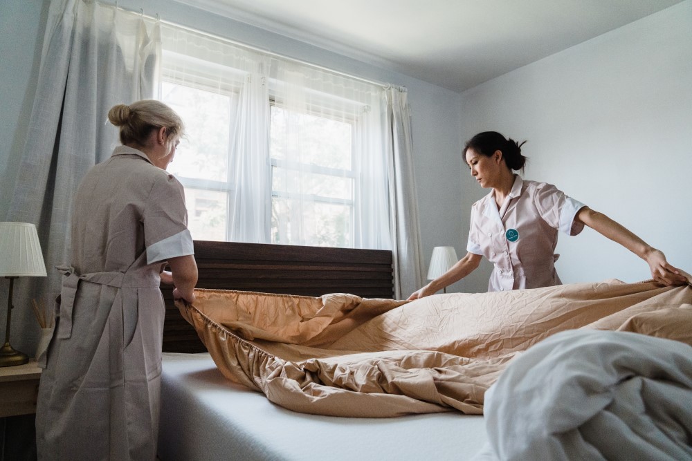 two women cleaners change some bed sheets