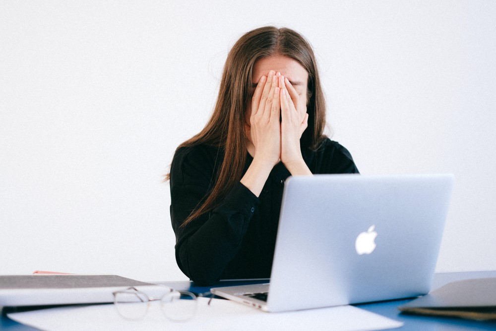 an employee hold their head in their hands stressed from work