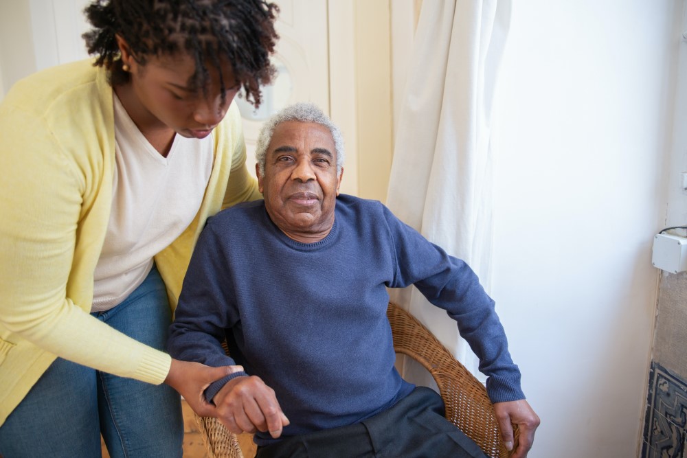 an elderly person is helped up from a chair by a relative