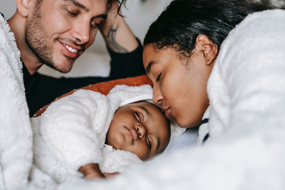 a mother and father lay down with their new born baby