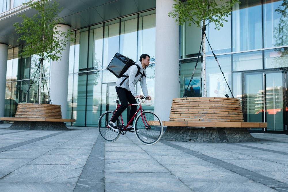 a food delivery man drives a bicycle with a box bag