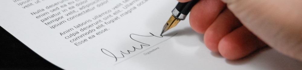 a person signs a document with a fountain pen
