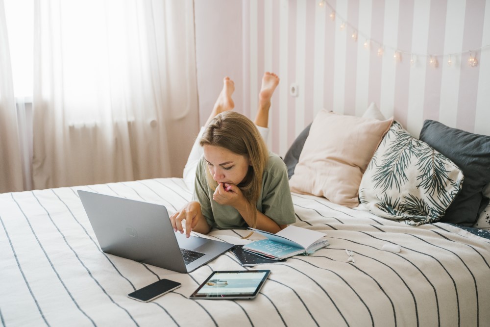 a women works on her bed with her laptop
